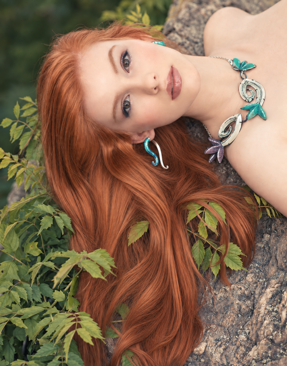 Turquoise and silver jewelry by Shana Kroiz with flowing red hair against rock and foliage